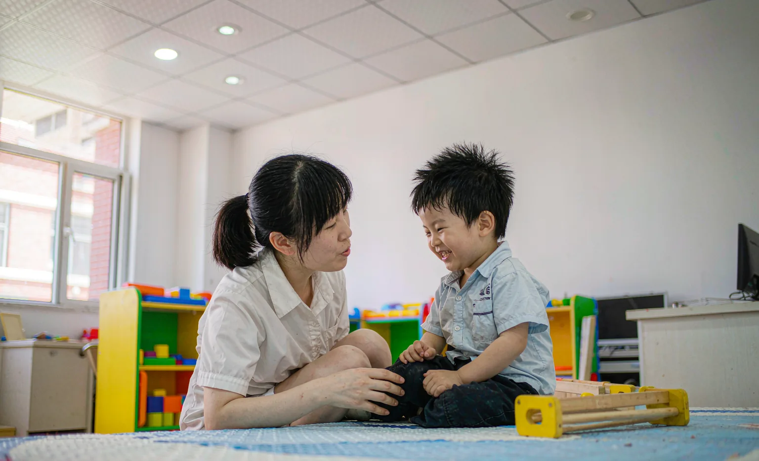 康复治疗师与孤独症儿童进行感统游戏训练